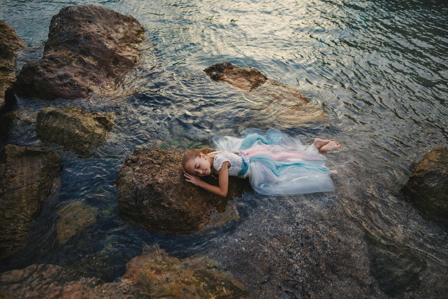 Niña tumbada rocas agua